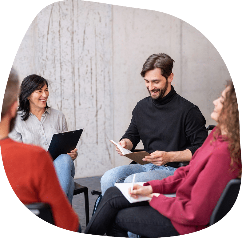 men and women sitting in a circle during group therapy reading and talking