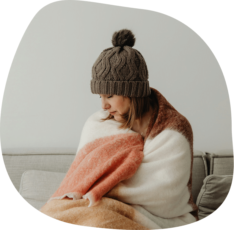 woman sitting in a couch wrapped in a blanket